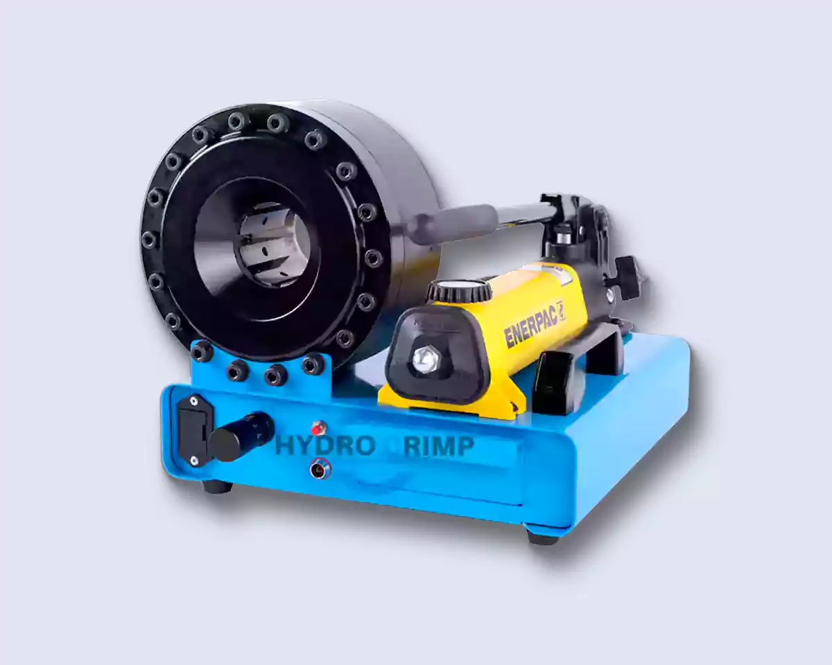 La prensa manual de mangueras HYDROCRIMP HC-P16MP sobre fondo claro: base azul con cajón de dados y luz indicadora, cabezal negro de dieciséis bulones con los segmentos de dado abiertos y una bomba manual Enerpac amarilla atornillada al costado
